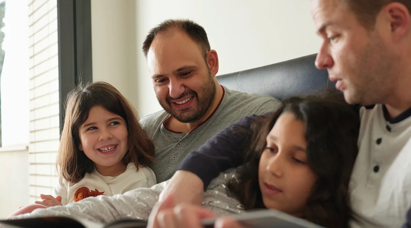LGBTQ dads reading to daughters at home