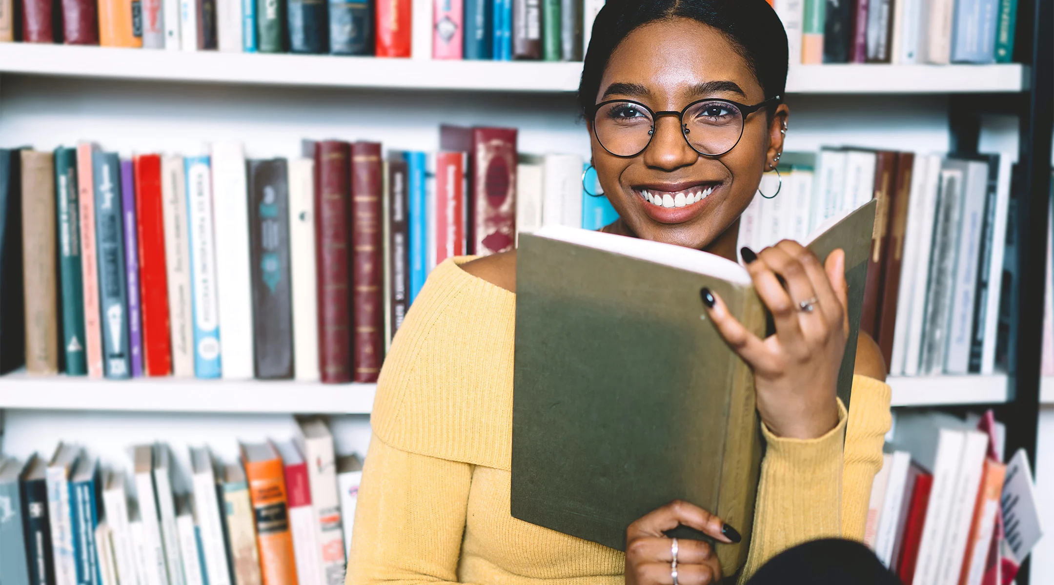 happy woman reading by book shelf