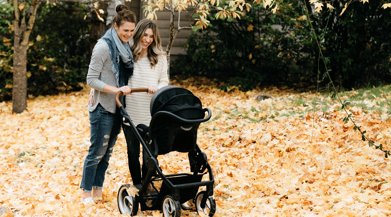 two moms pushing stroller outside during autumn