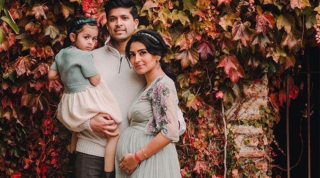 The author and her husband and daughter, pictured against wall with fall leaves. 