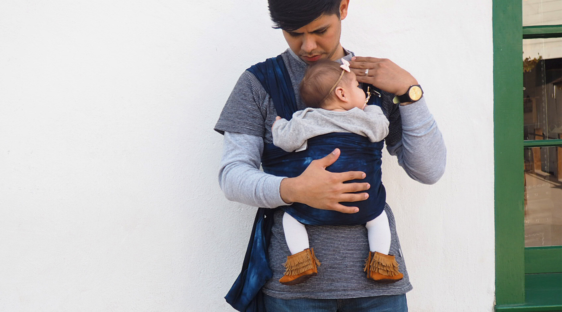 dad walking outside and holding baby correctly in carrier to avoid hip dysplasia