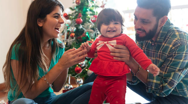 parents holding up baby in her red christmas outfit