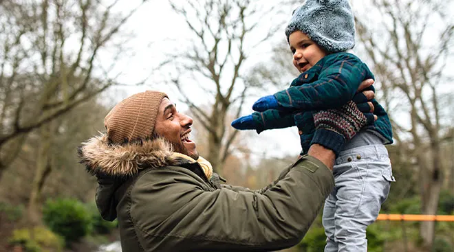 happy mom holding baby during winter in the snow