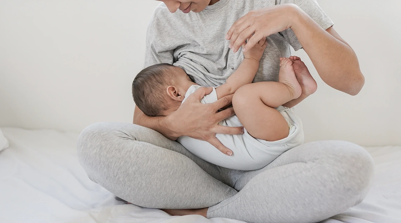 mother breastfeeding baby in bed at home