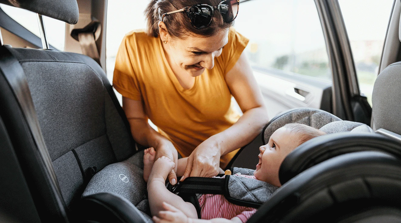 mother buckling baby into infant car seat