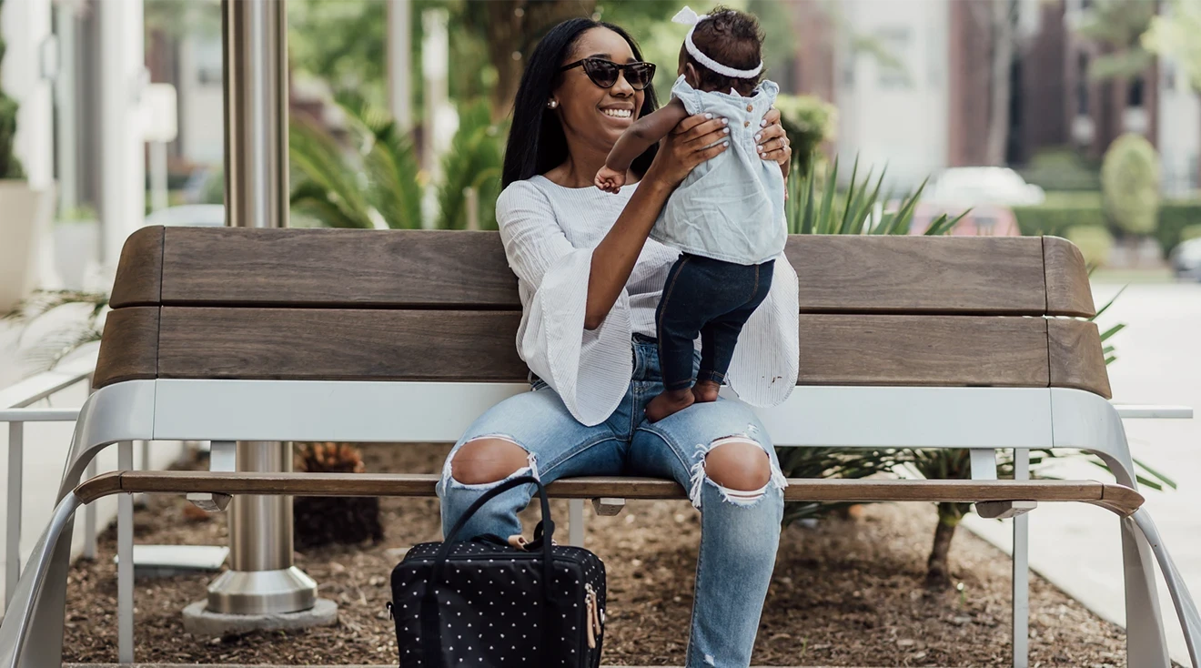 mother holding baby while sitting on bench outside