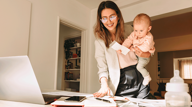 mother working at home while holding baby