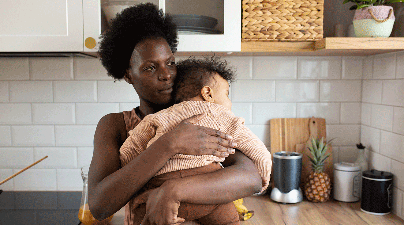 black mother holding baby at home