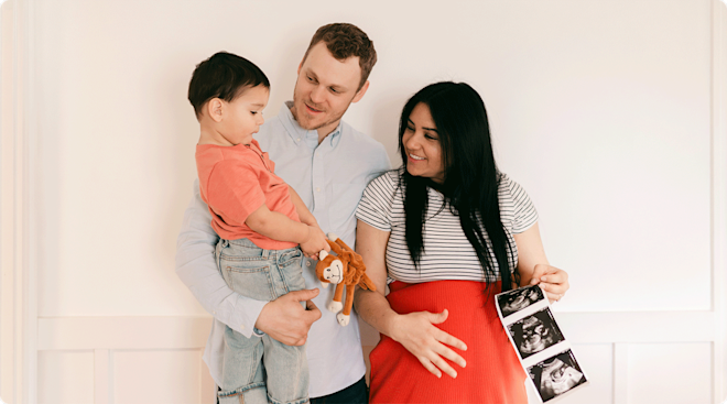 parents with toddler holding ultrasound photos pregnancy announcement 