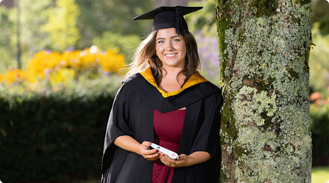Leah Shanahan in graduation cap and gown with pregnancy test for the blind
