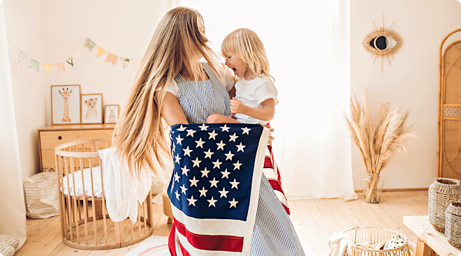 A mom holding her baby in nursery room with American flag.