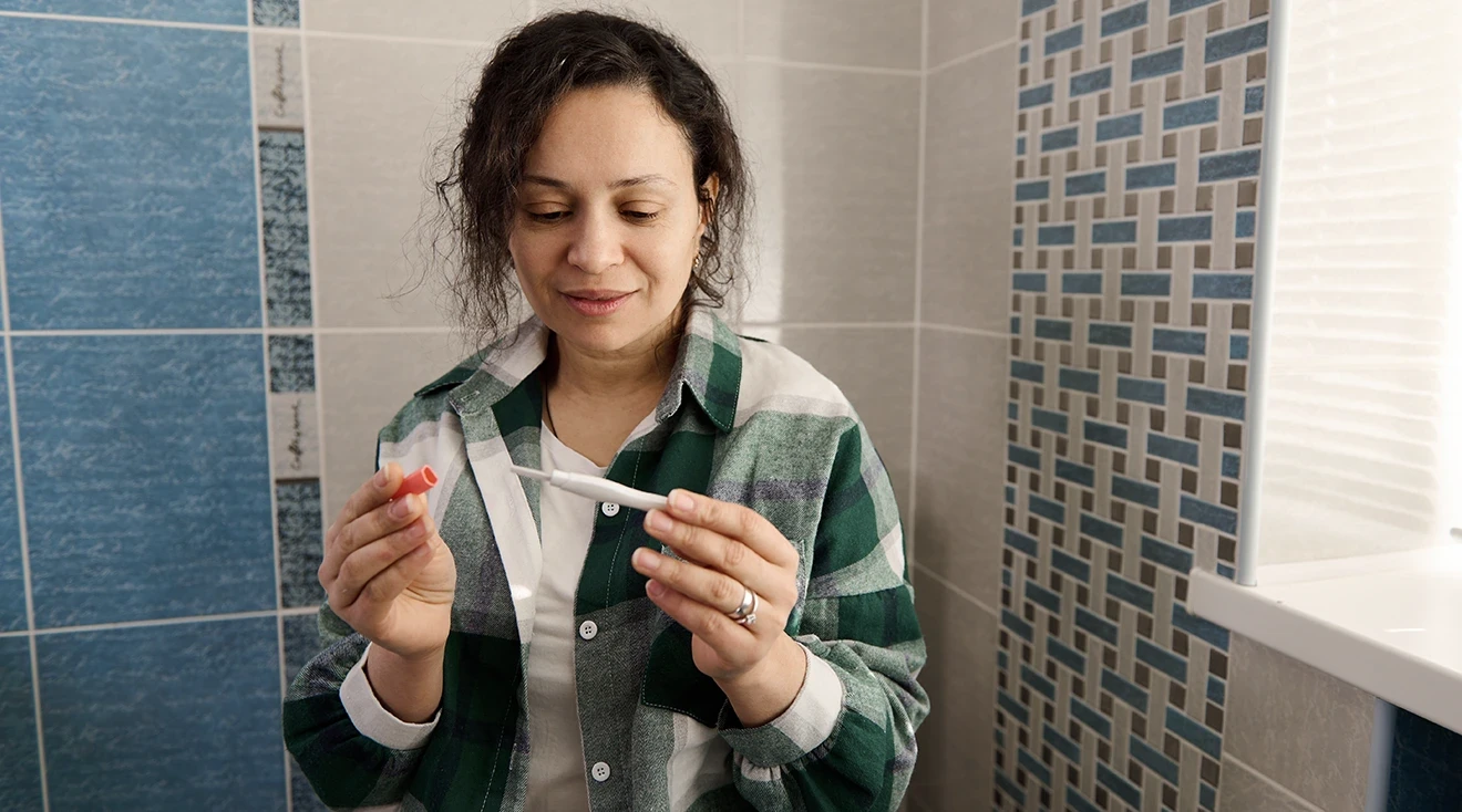 woman taking a pregnancy test in bathroom at home