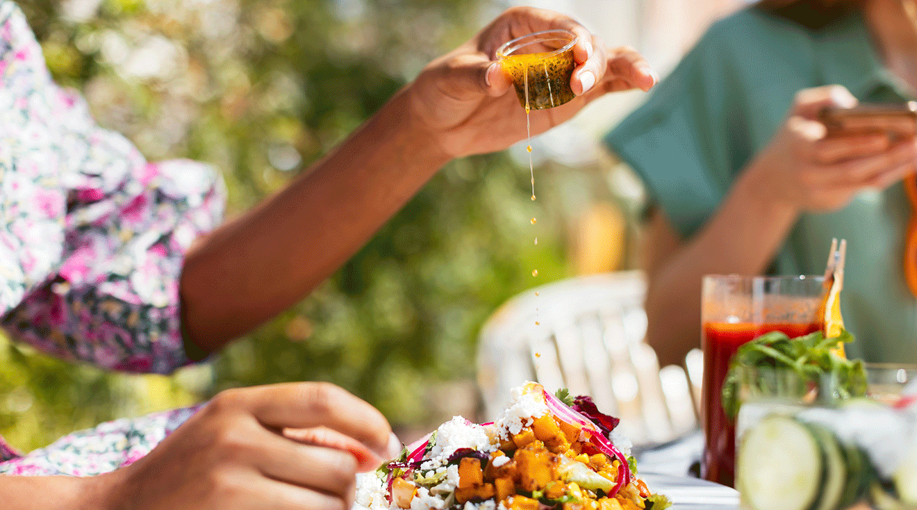 woman putting hot sauce on food