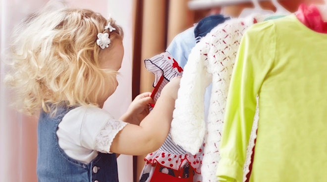 toddler girl choosing clothes from closet