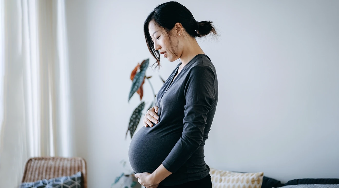 pregnant woman holding belly and looking down