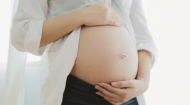 close up of pregnant person holding belly