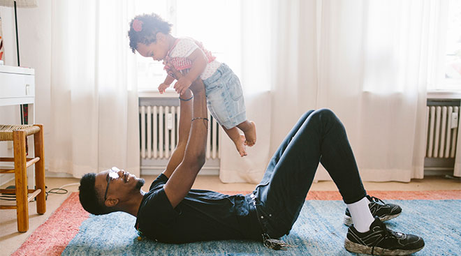 dad holding his toddler while laying on the floor at home