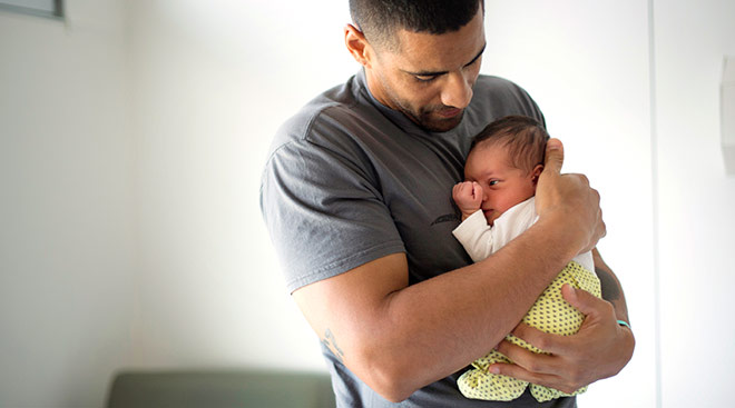 new dad holding his newborn baby close