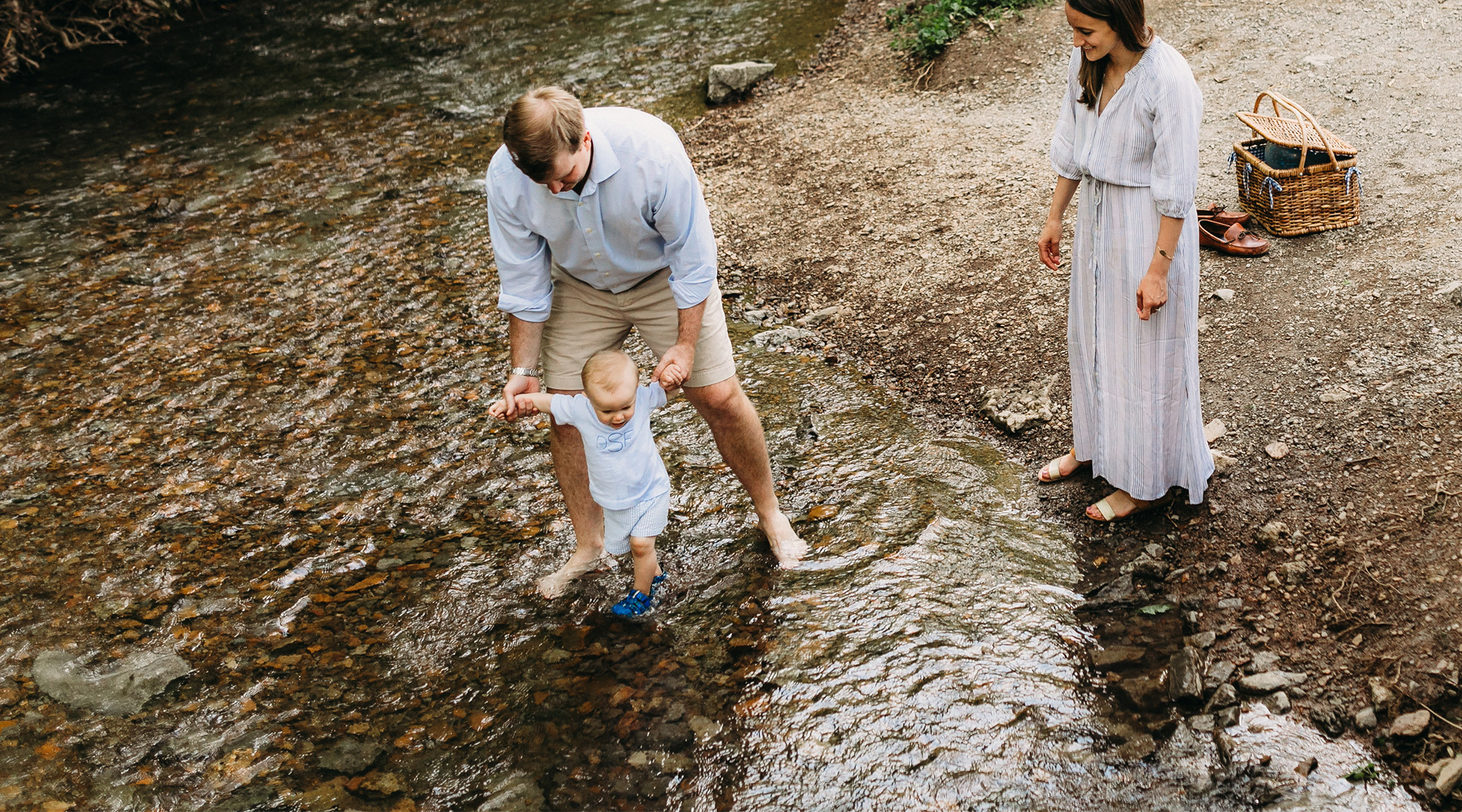 parents take baby on a walk by the creek for a summer time activity