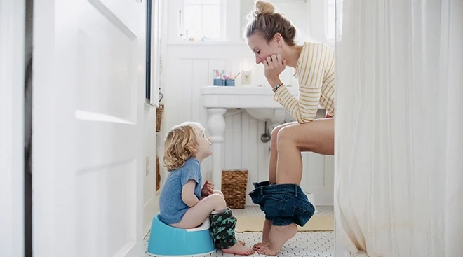 mom potty training toddler in bathroom