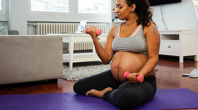 pregnant woman sitting down and lifting weights at home