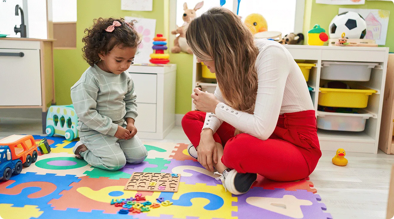 preschool teacher playing with toddler and puzzle