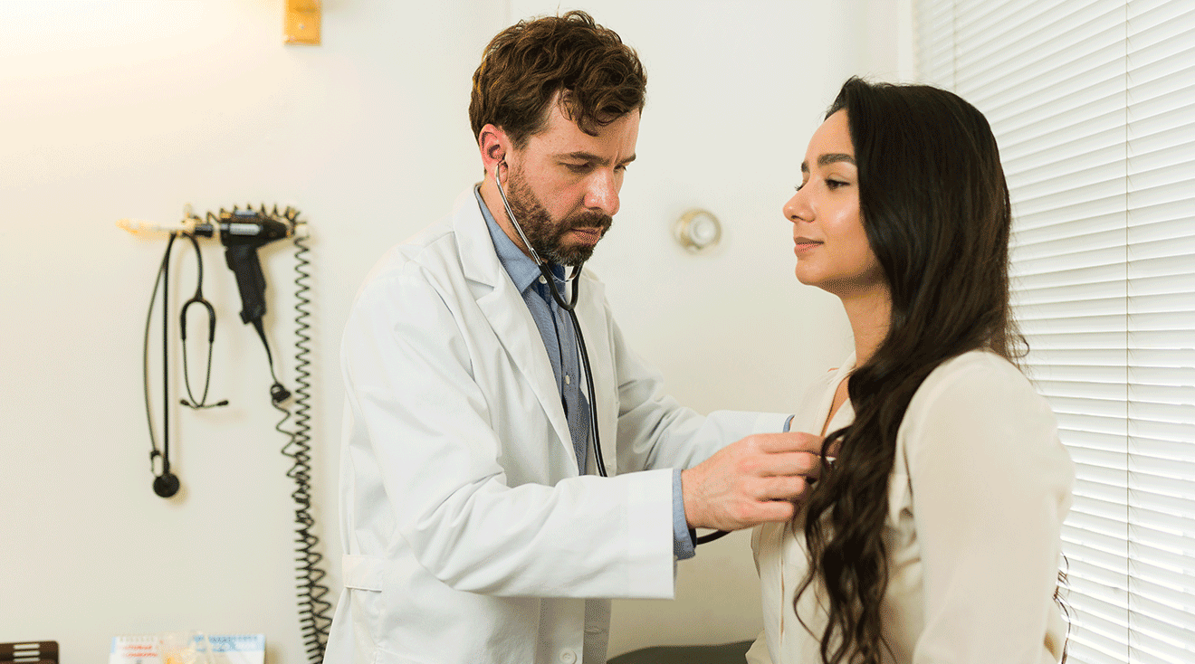 cardiologist checking woman's heart with stethoscope