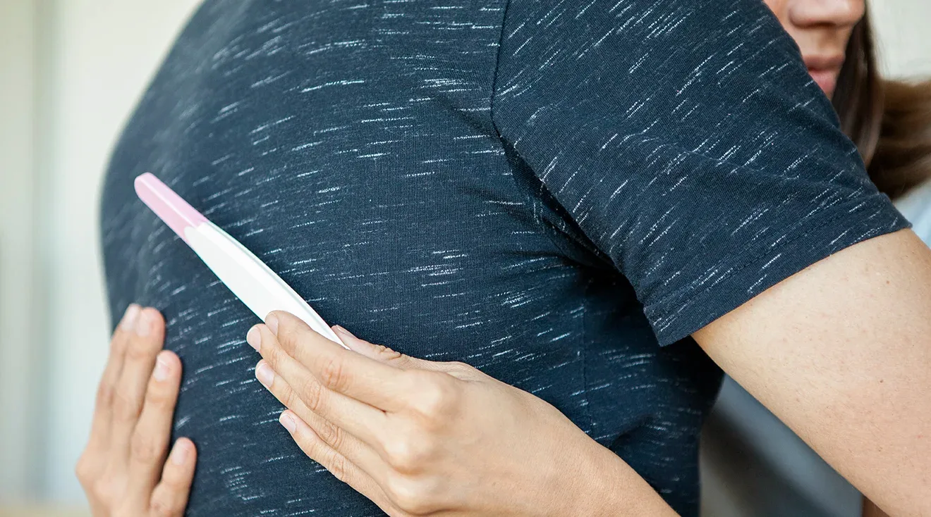 couple embracing while holding negative pregnancy test