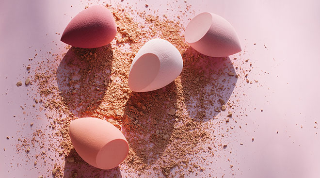 makeup powder and beauty blenders on pink background
