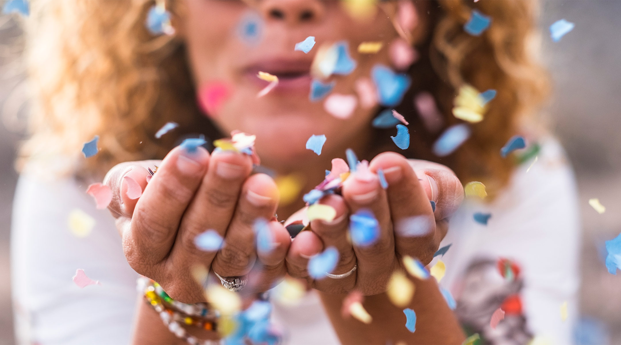 woman blowing confetti at gender reveal