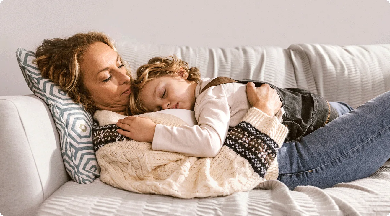 mother and child lying on couch at home