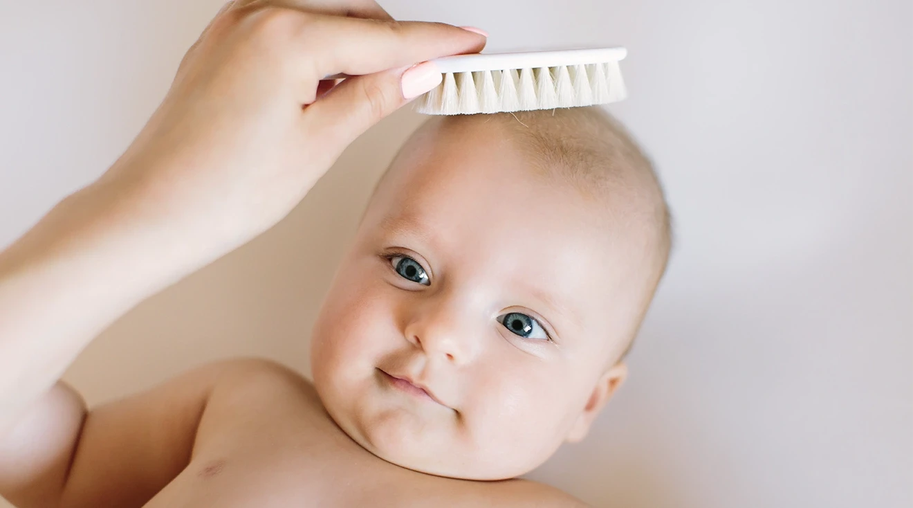 mother brushing baby's hair with baby hair brush