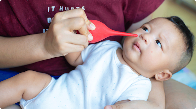 mom using bulb syringe to clear baby congestion
