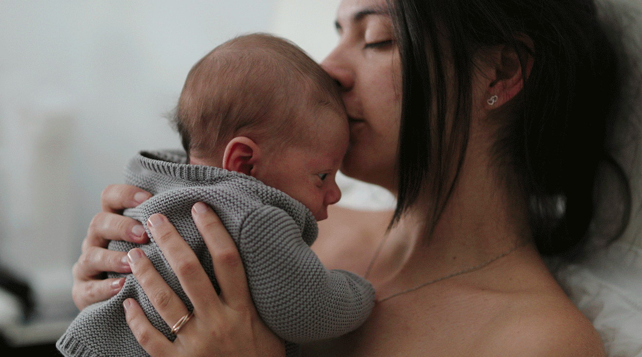 tired mother kissing newborn baby