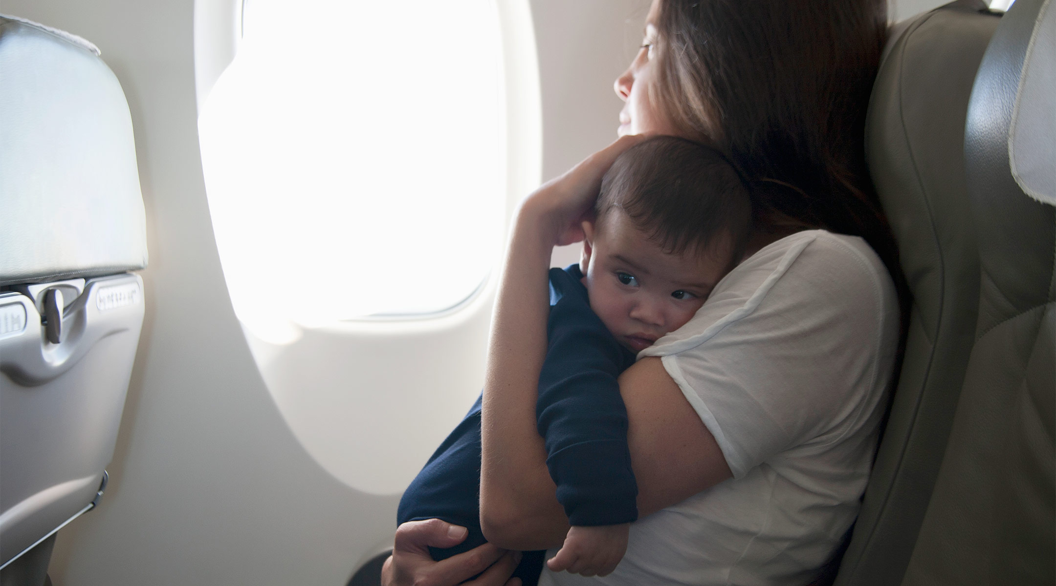 mom holding upset baby on airplane