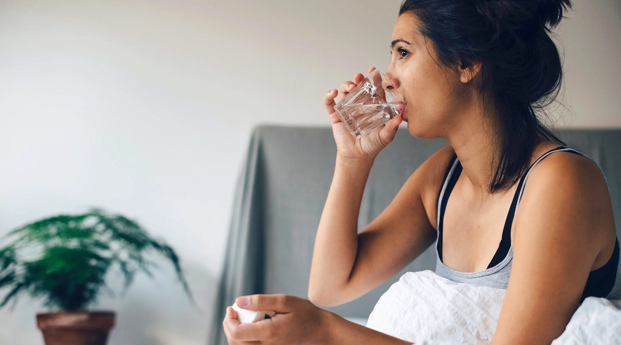 sick woman in bed drinking water