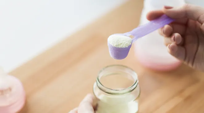 close up of mother making a formula bottle for baby