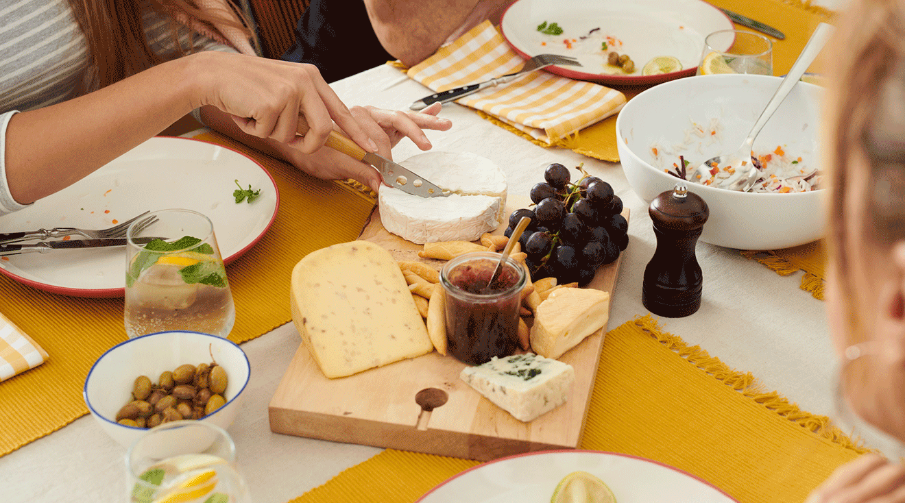 woman cutting soft cheese on cheese board