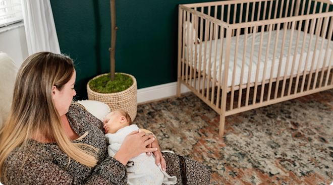 mom holding baby in baby nursery