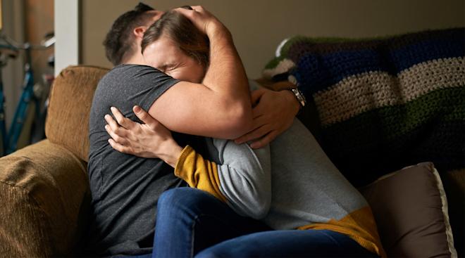 very sad crying couple embracing on the couch