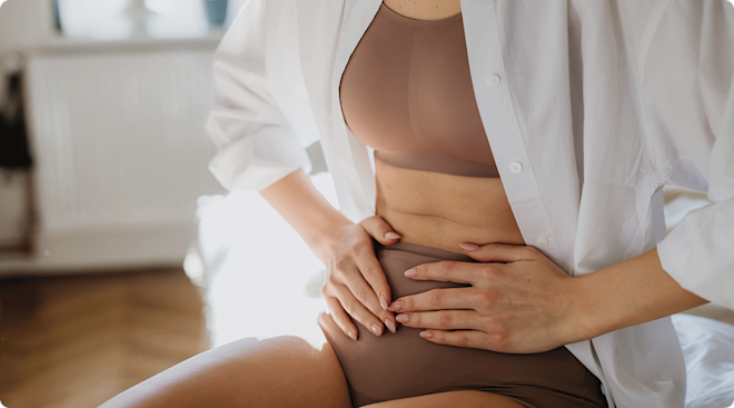 A close up of a woman with her hands on her abdomen.