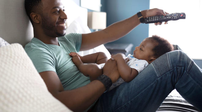 baby and dad watching tv, as dad uses the remote control