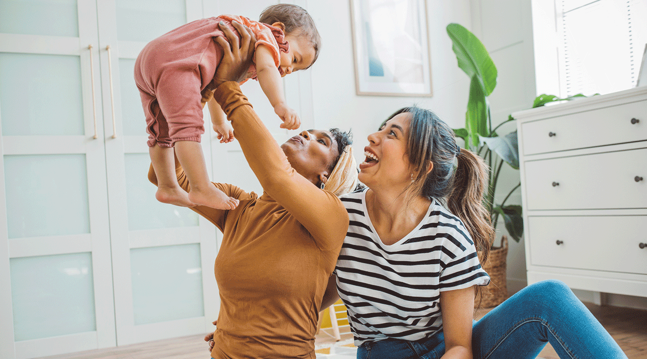 two moms playing with baby at home