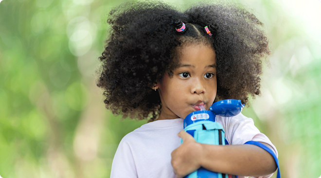 child drinking out of reusable water bottle outside