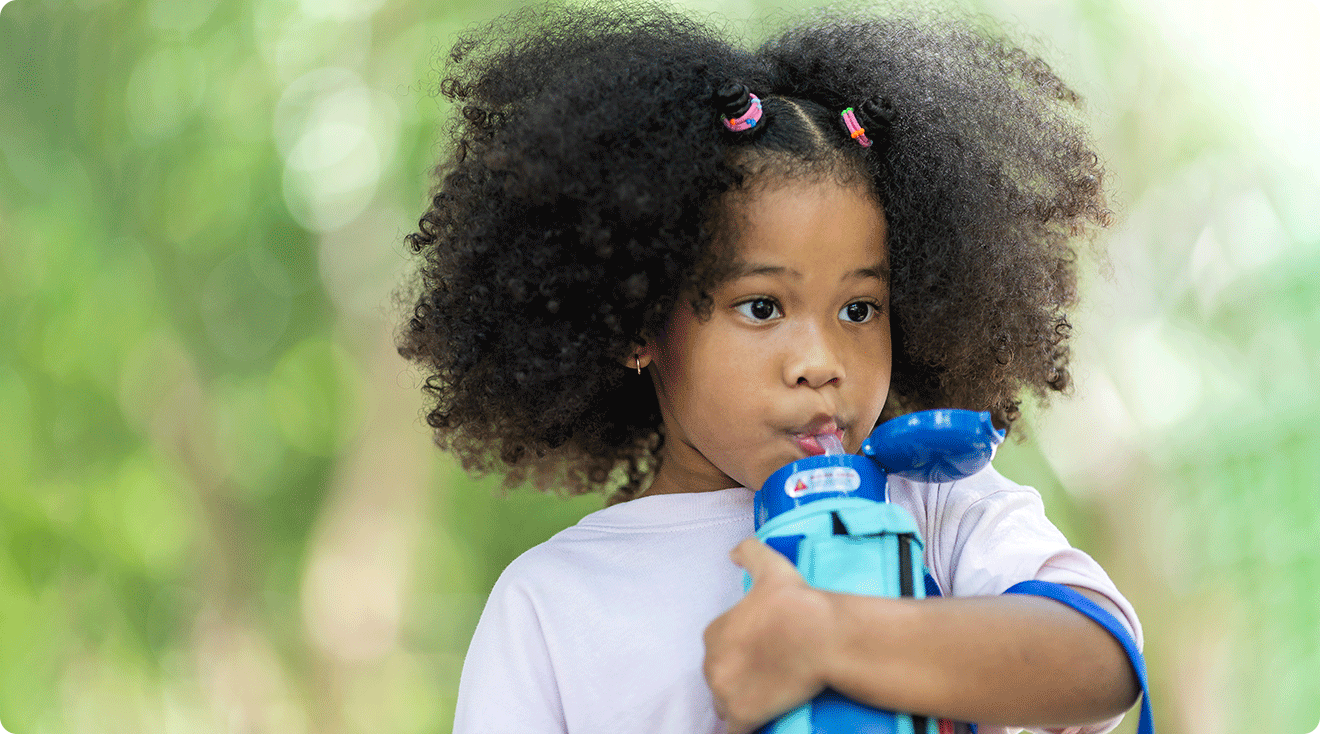 child drinking out of reusable water bottle outside