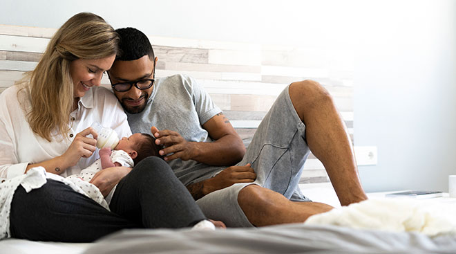 mother and father on bed with newborn photoshoot