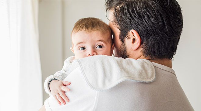 dad holding his newborn baby while burping him