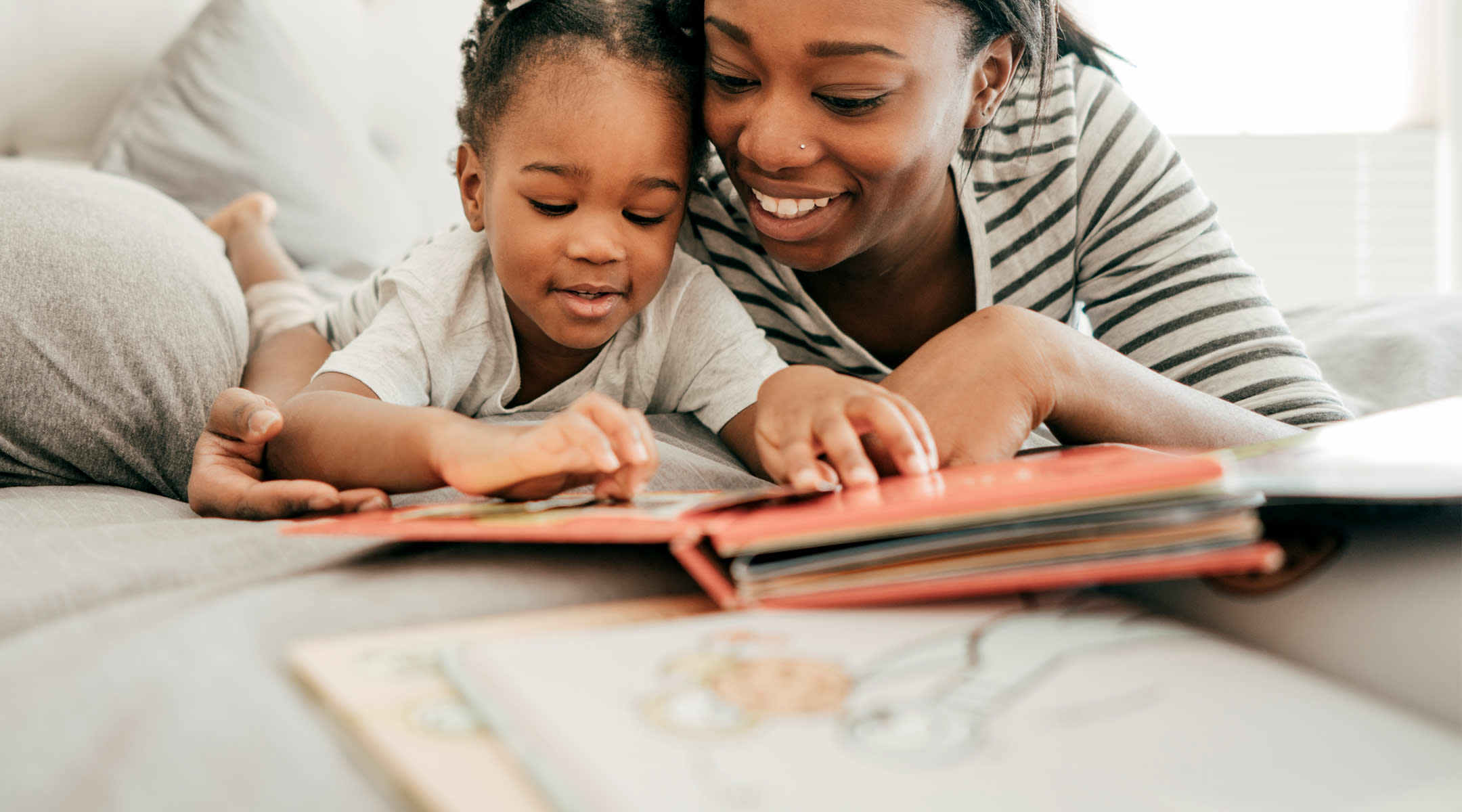 mom snuggling with her daughter while reading books