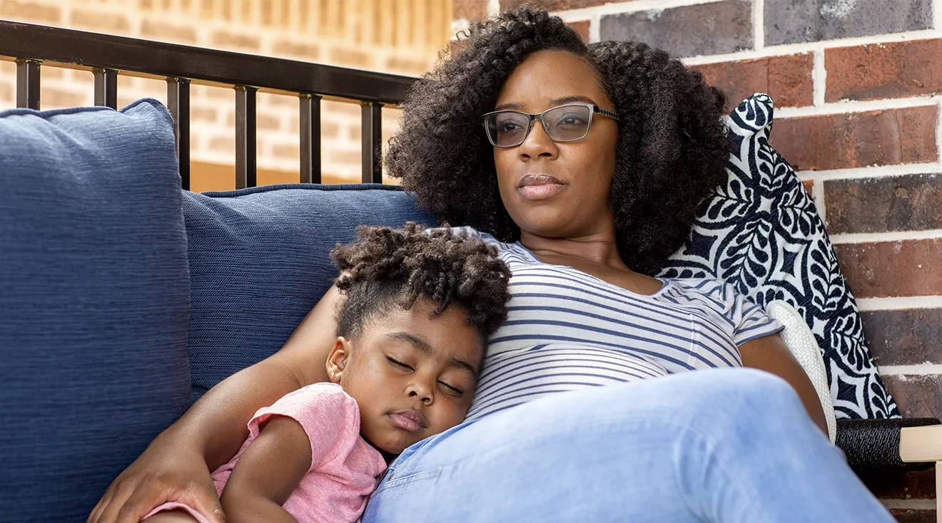 anxious mother sitting with sleeping daughter