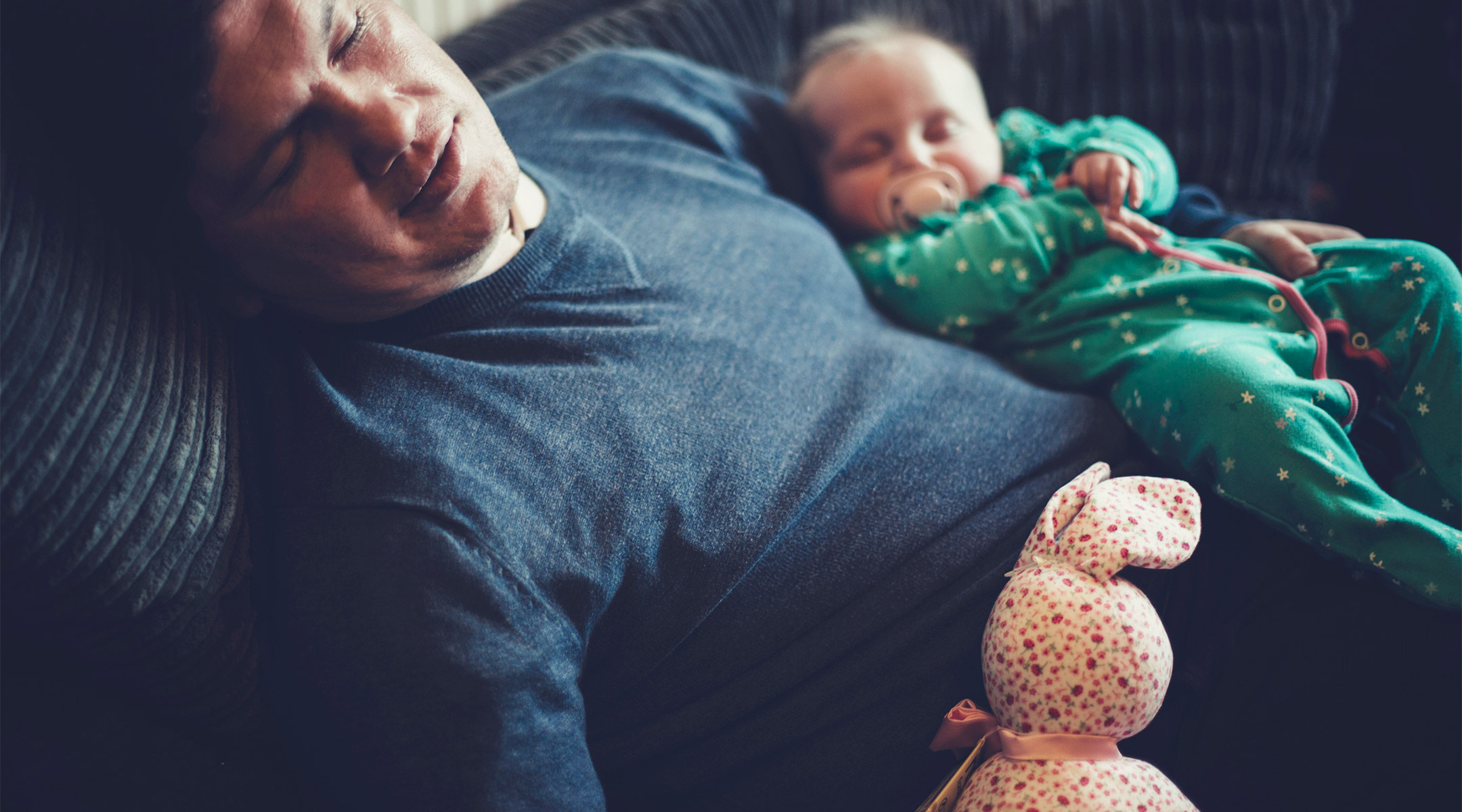 dad sleeping with baby on couch at home